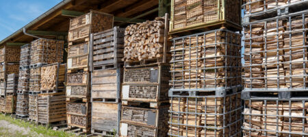 Gestapelte Gitterboxen gefüllt mit Holz